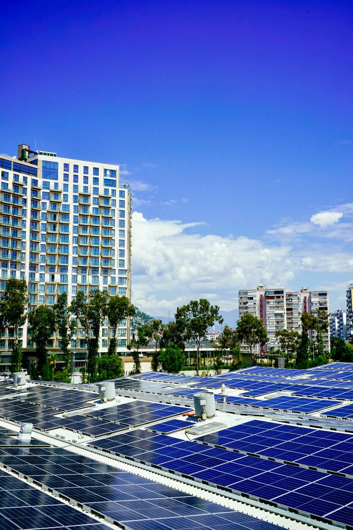 our-stories High-rise buildings and a large solar panel array under a clear blue sky.